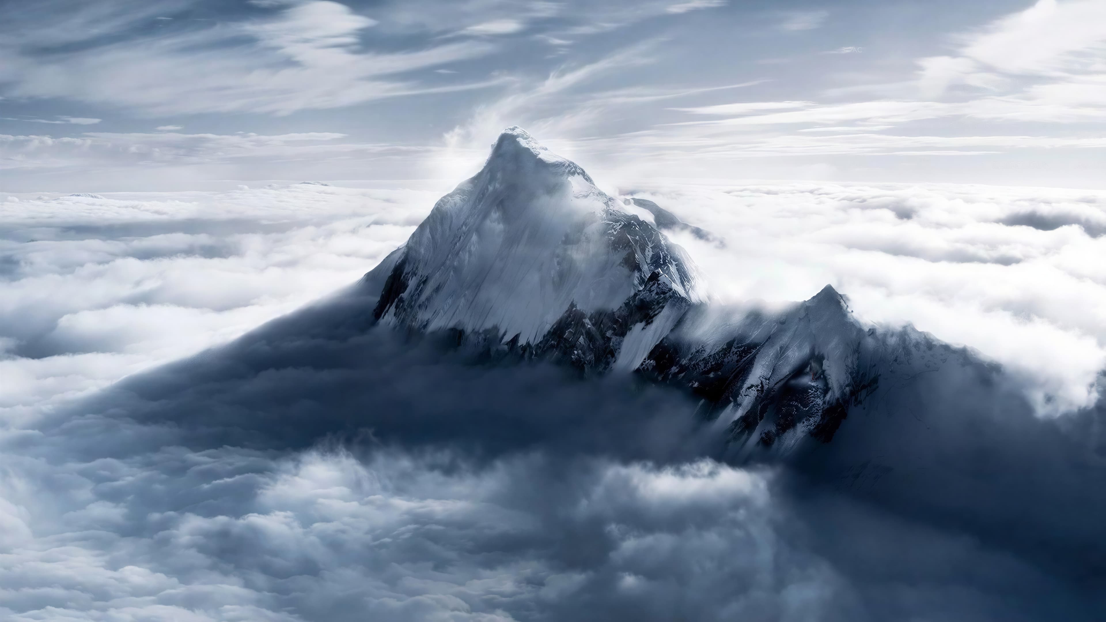 Aerial view of a snowy summit rising above a sea of clouds